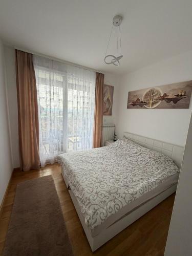 a bedroom with a bed and a large window at Bagdala apartman Krusevac in Kruševac