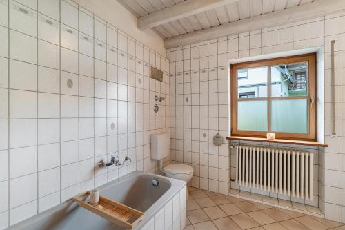 a bathroom with a tub and a toilet and a window at Felsenland Idyll in Erfweiler