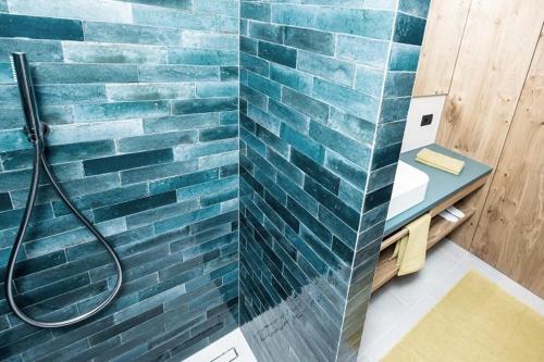 a bathroom with a blue tile wall and a shower at Mysciliar Apartment Sky ii in Siusi