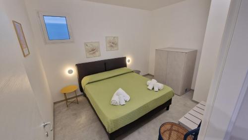 a bedroom with a green bed with towels on it at Villa Taliala in Alcamo Marina
