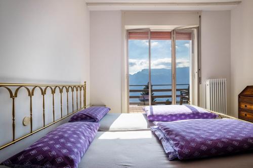 a bedroom with two beds with purple pillows and a window at Wohnung mit grandiosem Ausblick in Tremosine Sul Garda