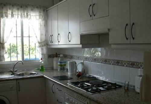 a kitchen with white cabinets and a stove top oven at Casa Galesa in Nerja