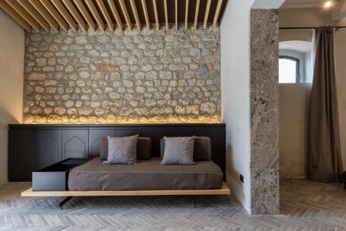 a bed in a room with a stone wall at Suite Mezzatorre in San Gimignano
