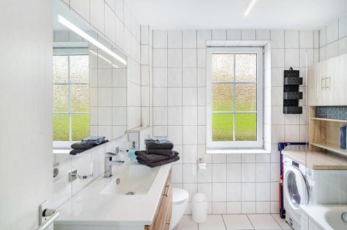 a white bathroom with a sink and a washing machine at Ferienwohnung am West-östlichen Tor in Ecklingerode