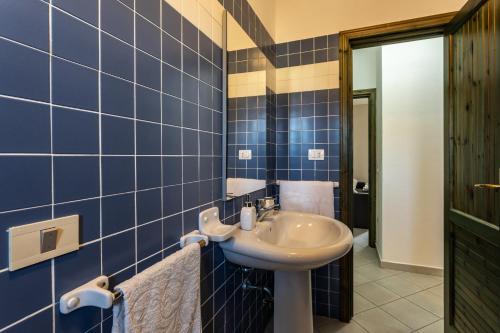 a bathroom with a sink and a blue tiled wall at Casamorle in Isola Rossa