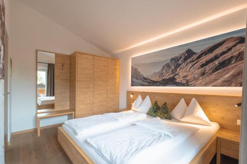 a bedroom with a white bed with a painting on the wall at Kriendl Nr 3 in Valdaora