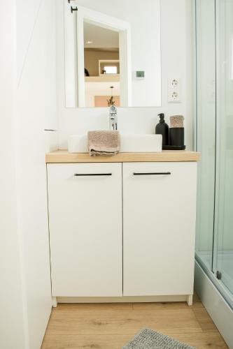 a white bathroom with a sink and a mirror at Tiny Om Ferienhaus in Laichingen
