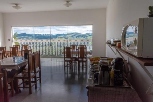 una sala da pranzo con tavolo, sedie e una grande finestra di Pousada Lourenço a Nazaré Paulista