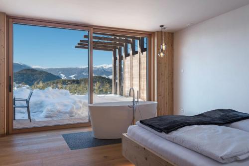 a bedroom with a tub and a large window at Aura Chalets - Nr 4 in Castelrotto