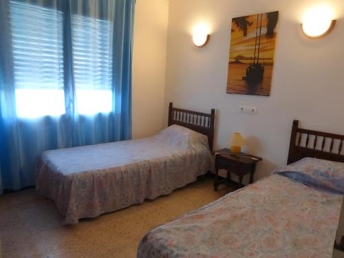 a bedroom with two beds and a window with blue curtains at Villa Sylvie- Cerca Playa Riells- 4 in L'Escala