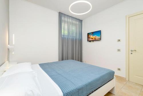 a white bedroom with a bed and a window at Orizzonte Damare in Volastra