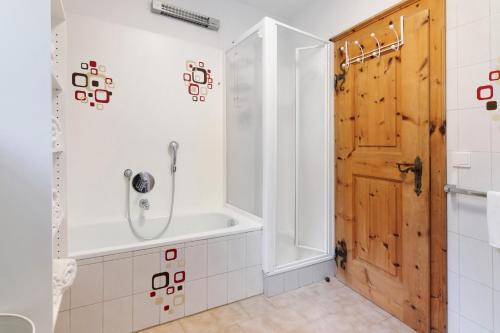 a bathroom with a tub and a wooden door at Bertollhof Apfelerlebnis in Silandro