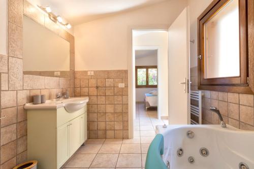 a bathroom with a tub and a sink and a mirror at Villa Amalthea - sea view-wellness in Costa Paradiso