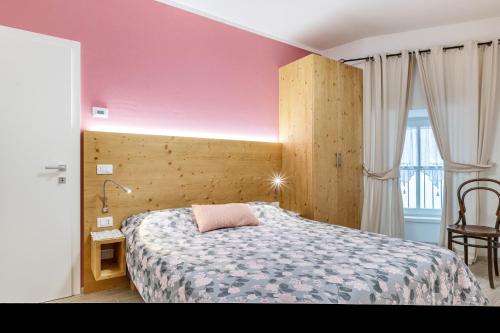 a bedroom with a bed and a pink wall at L'antica corte apt Angelina in Levico Terme