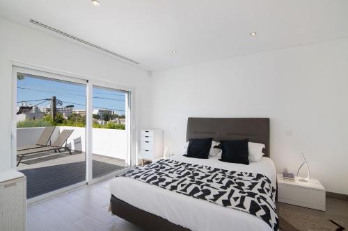 a white bedroom with a bed and a balcony at Pine Lodge in Vilamoura