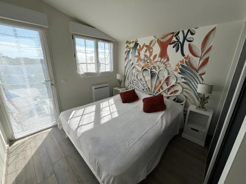 a bedroom with a white bed with red pillows on it at Villa des sablons, piscine chauffée in La Tranche-sur-Mer