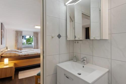 a white bathroom with a sink and a bedroom at Ferienwohnung Selbecke in Kirchhundem