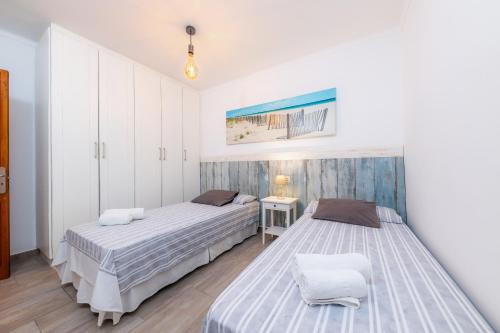 a bedroom with two beds and a table with a lamp at Casa Cantino in Santa Margalida