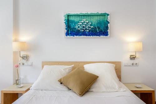 a bed with white sheets and a painting on the wall at Edificio can Sord Apto nº 2 in La Savina
