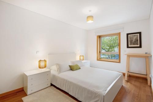 a white bedroom with a bed and a window at Mary House in Matosinhos