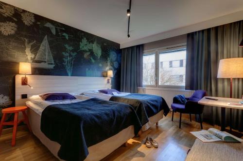 a hotel room with two beds and a desk at Scandic Linköping Väst in Linköping