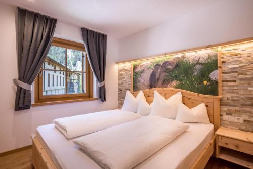 a bedroom with a white bed with a painting on the wall at Lechnerhof Fane Alm in Valles