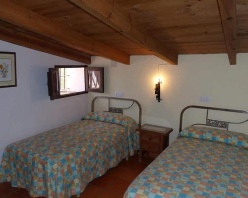 a bedroom with two beds and a table and a window at Granados in Fuenteheridos