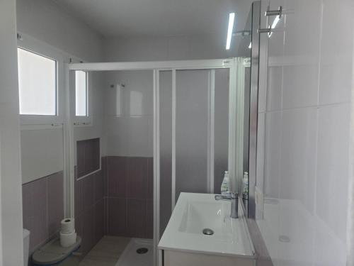 a white bathroom with a shower and a sink at Loft Molinos Atalaya in San Bartolomé