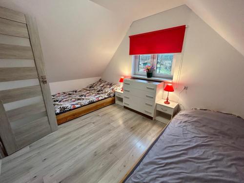 a bedroom with a bed and a dresser and a window at Gaj za Rzeką GNAP in Prusie