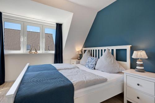 a bedroom with a bed with blue walls and windows at Ferienhaus Düün Drööm in Ording