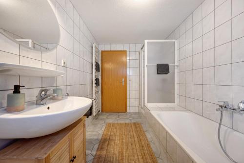 a bathroom with a white sink and a tub and a shower at Ferienwohnung Malia in Neubulach