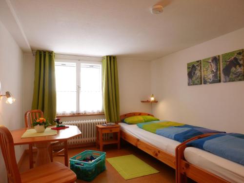 a bedroom with a bed and a table and a window at Haus Trötschler in Weilheim