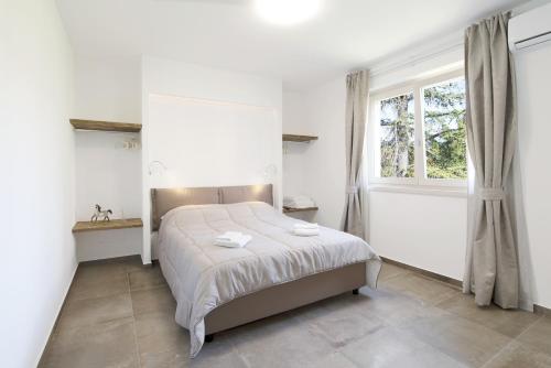 a white bedroom with a bed and a window at Appartamenti Dama 2 in Bardolino