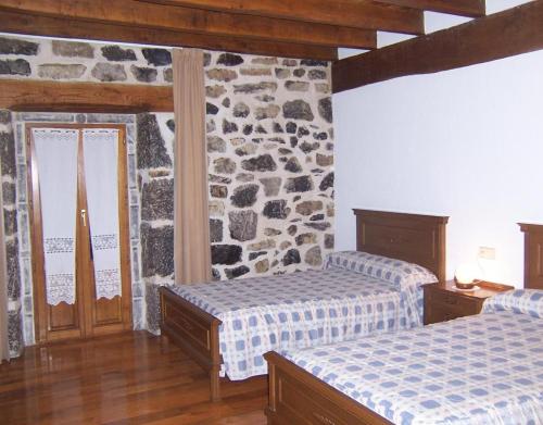 a bedroom with two beds and a stone wall at Casa Rural Barbonea in Lekunberri