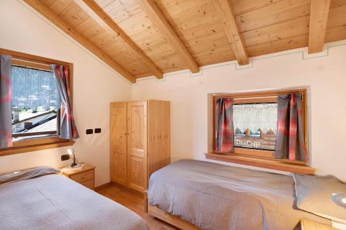a bedroom with two beds and two windows at Appartamento Jolly in Livigno