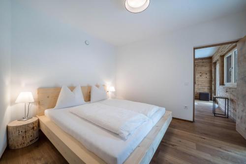 a bedroom with a large white bed and a mirror at Naturapartments Alpreid Altholz in San Pancrazio dʼUltimo