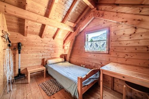 a bedroom in a log cabin with a bed and a window at Chalet 4p Simple - La Gélinotte in Verchaix