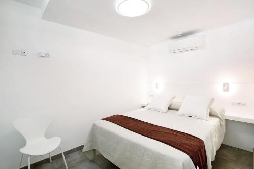 a white bedroom with a bed and a white chair at Tamaran Bureba 511 in Maspalomas