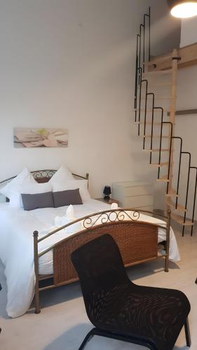 a bedroom with a bed and a black chair at Studio charmant avec jardin in Saint-Rémy-de-Provence