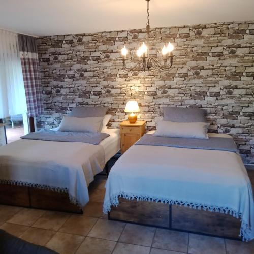 two beds in a room with a brick wall at Eifelstube Langerwehe in Langerwehe