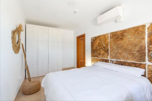 a bedroom with a white bed and a brick wall at Ecoturismo Calblanque in Las Barracas