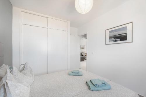a white bedroom with a bed with two towels on it at casa agua y sol 2 in Poris de Abona