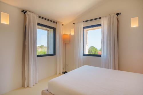 a bedroom with a white bed and two windows at Casa La Petite in San Pantaleo