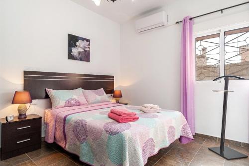 a bedroom with a bed with pink and purple sheets at Chalet Rocío - solo familias in Conil de la Frontera