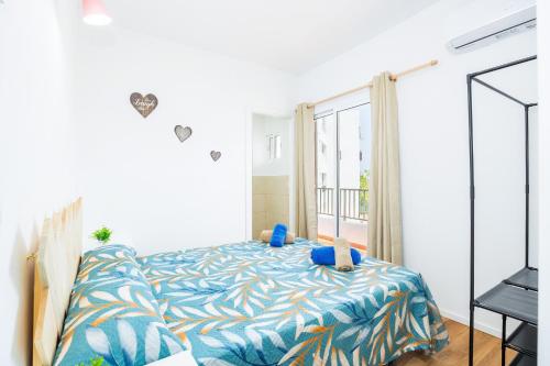 a bedroom with a bed with blue sheets and a window at Gran Sol Family 5 in Felanitx