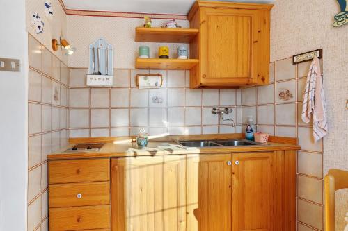 a small kitchen with wooden cabinets and a sink at Casa Zarina Well-kept Two-room in Cavalese