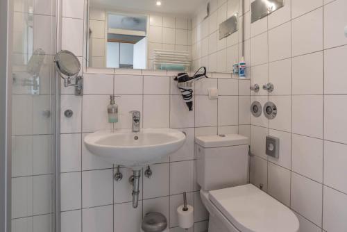 a white bathroom with a sink and a toilet at Fewo Blick über Sylt in Westerland