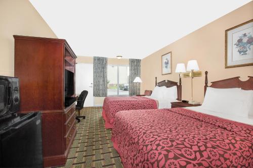 a hotel room with two beds and a flat screen tv at Meridian Inn in Meridian