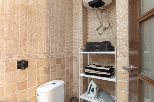 a bathroom with a toilet and aige tiled wall at Paraíso Radazul in Radazul