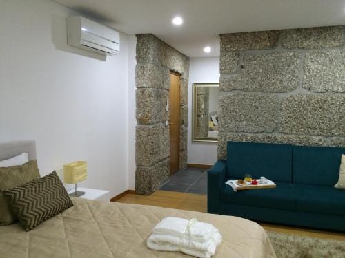 Casa do Sobreira في فييرا دو مينهو: غرفة نوم مع أريكة زرقاء وجدار حجري